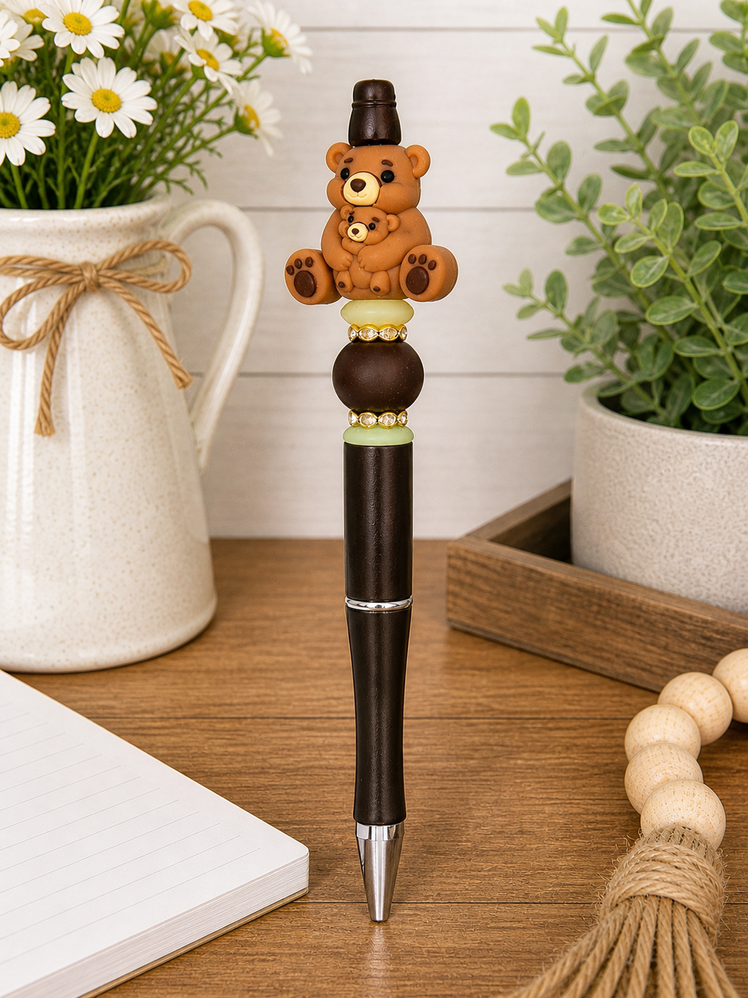 Black bear pen with teddy bear charm and green bead ring near tip.