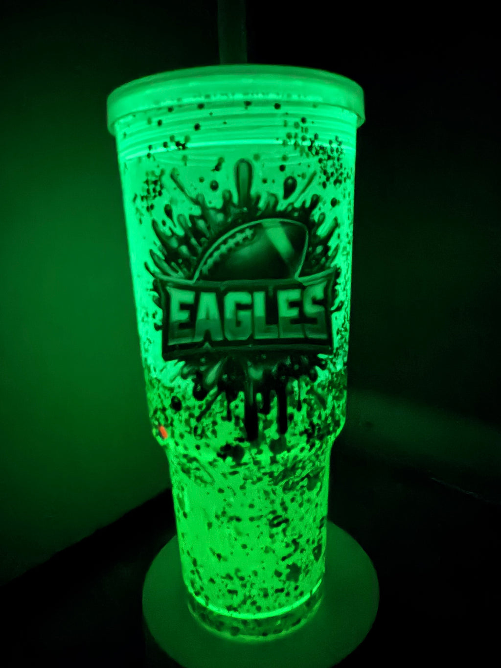 Glowing green acrylic lava tumbler with Eagles logo, illuminated speckled drip design
