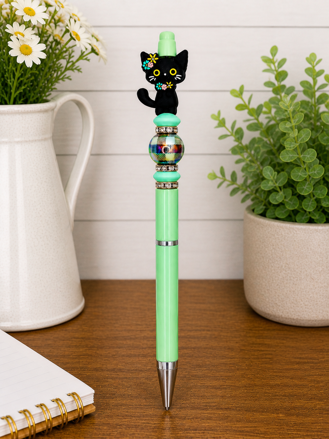 Green novelty pen with black cat figurine, flower details, and silver tip