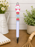 Cat pen with white cat topper, pink scarf, blue barrel, stacked gold charm accents
