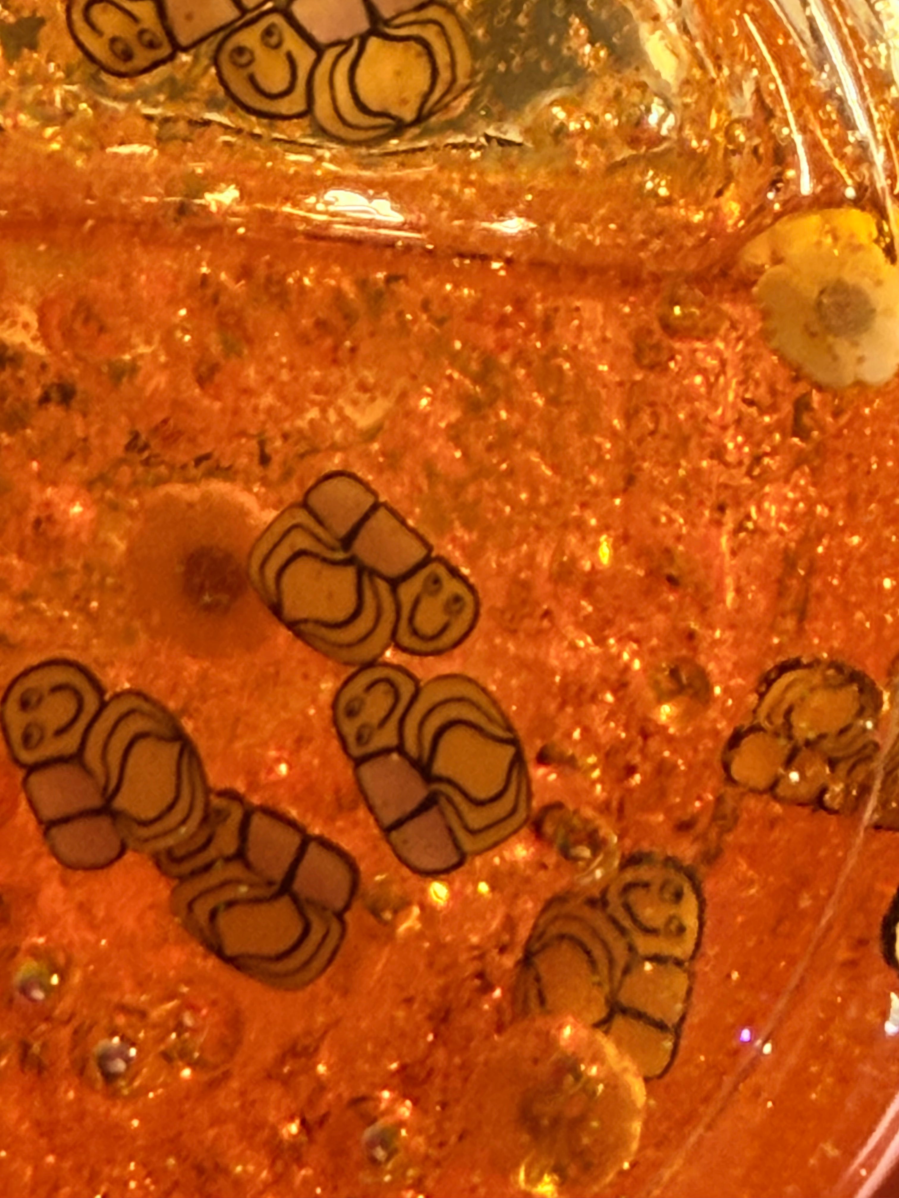 Close-up of amber glitter acrylic tumbler with bee and honeycomb-style embossing
