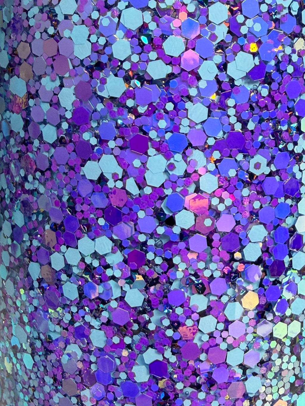 Close-up of multicolor holographic glitter hex confetti on cup surface