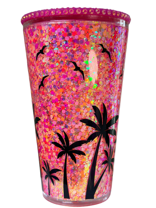 Glitter acrylic snow globe tumbler with pink-orange sparkle and black palm tree graphic