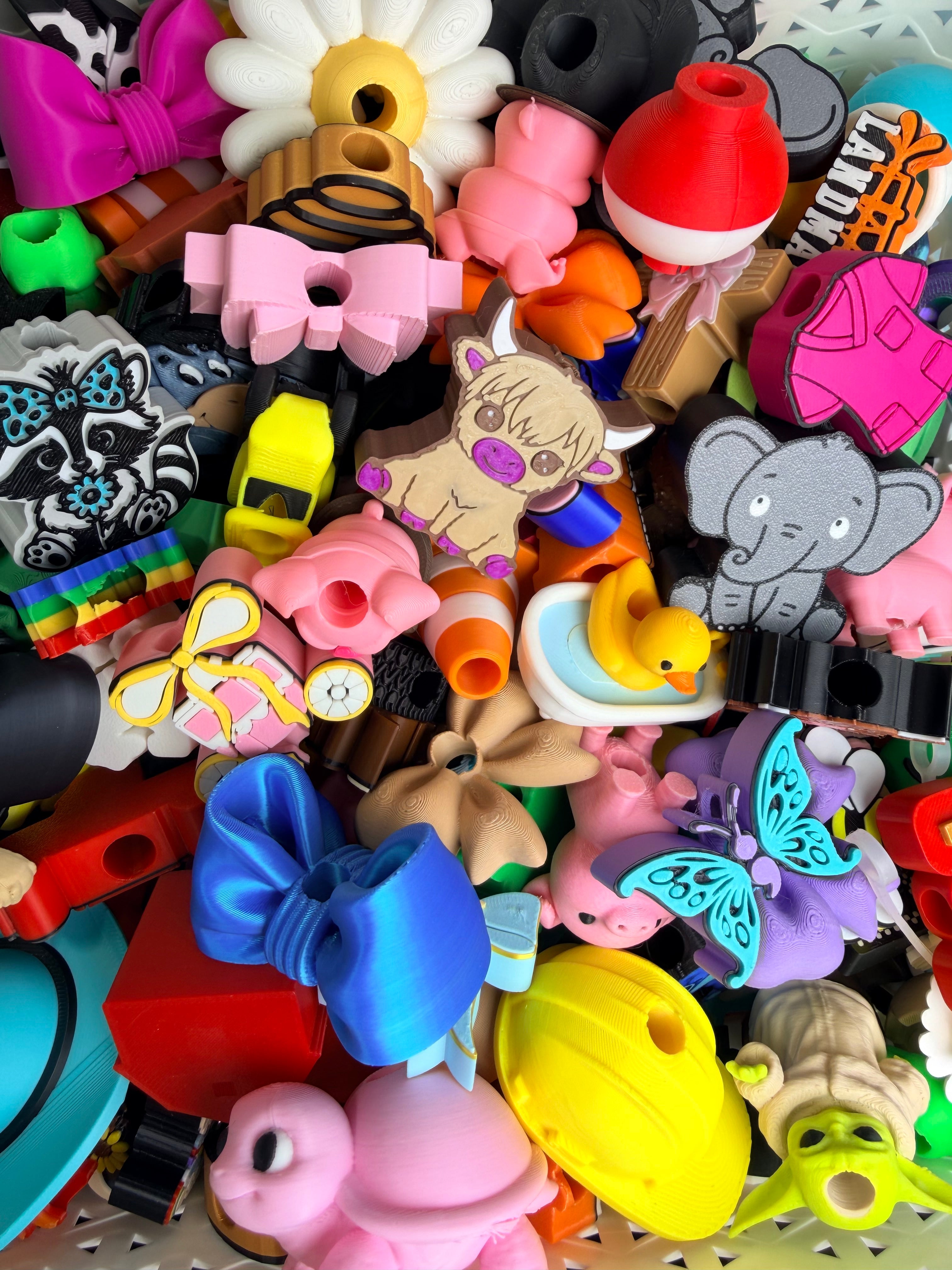 Colorful straw toppers with animal and butterfly shapes in a mixed pile