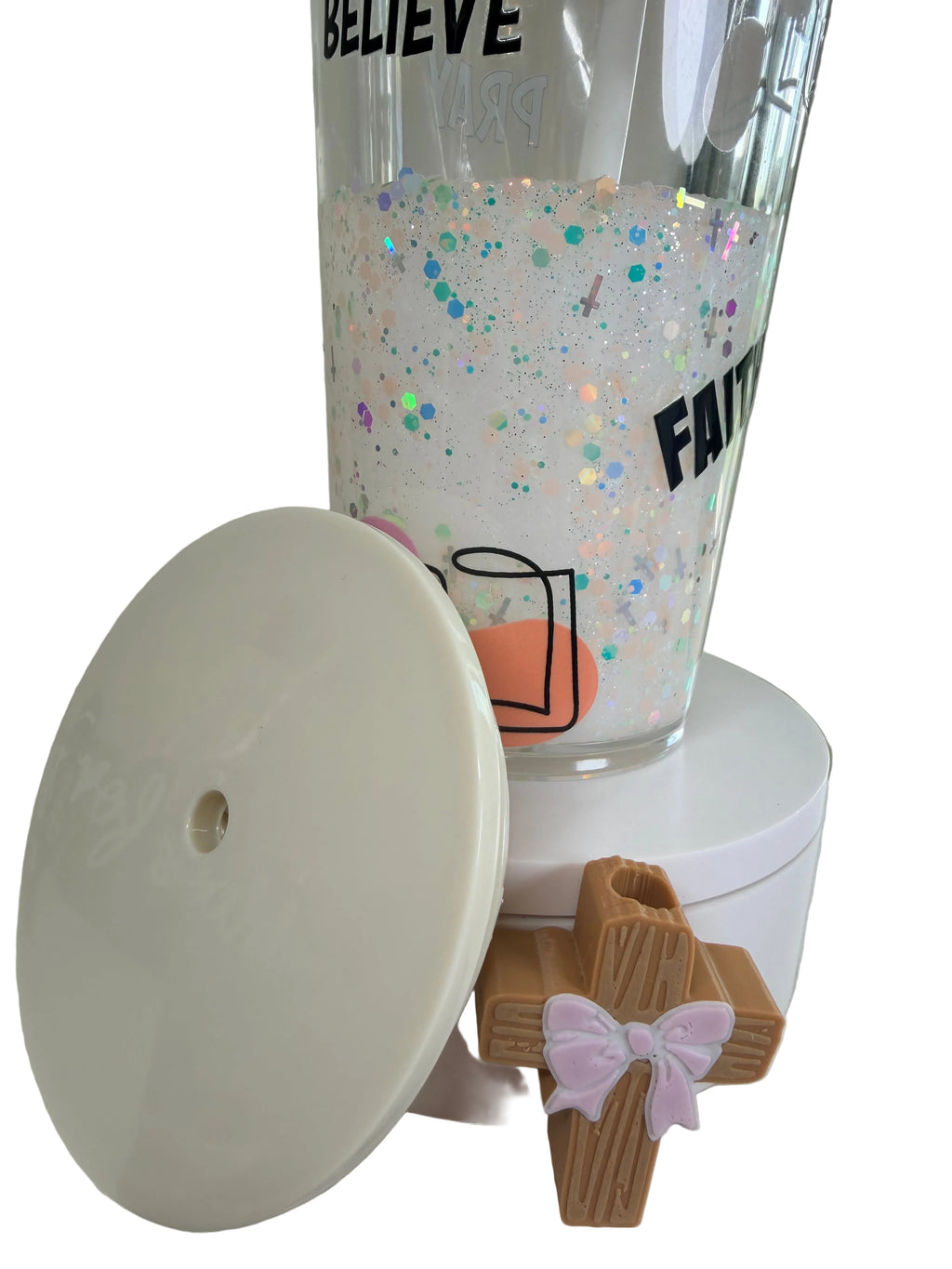 Clear acrylic tumbler with open white lid, cross charm, and pink bow topper