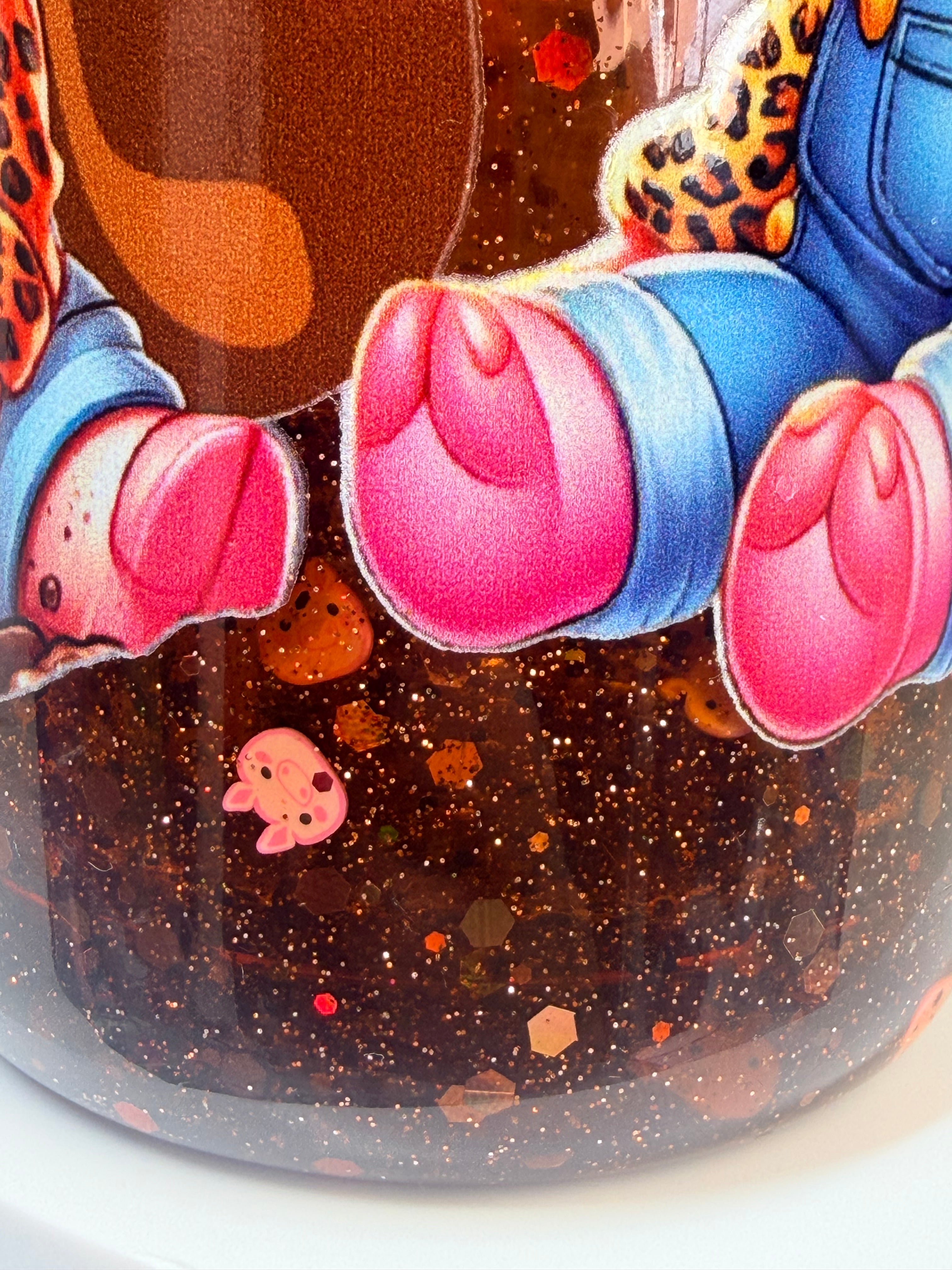 Acrylic snow globe tumbler close-up of glittery base with pig boots and hands