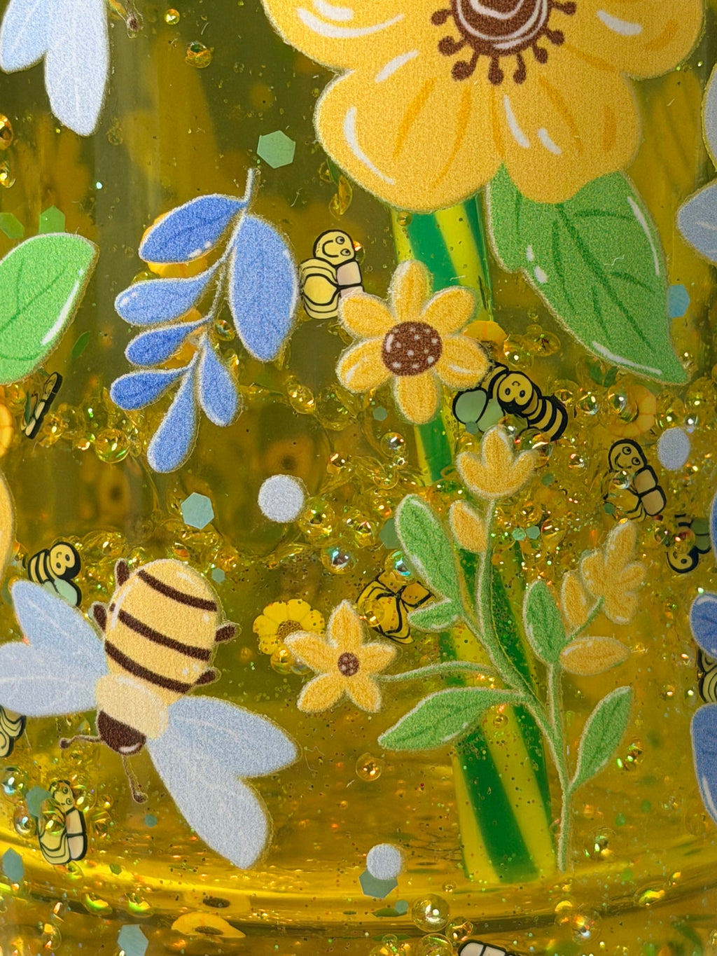 Close-up of green mug design with bees, flowers, and glittery gold resin texture