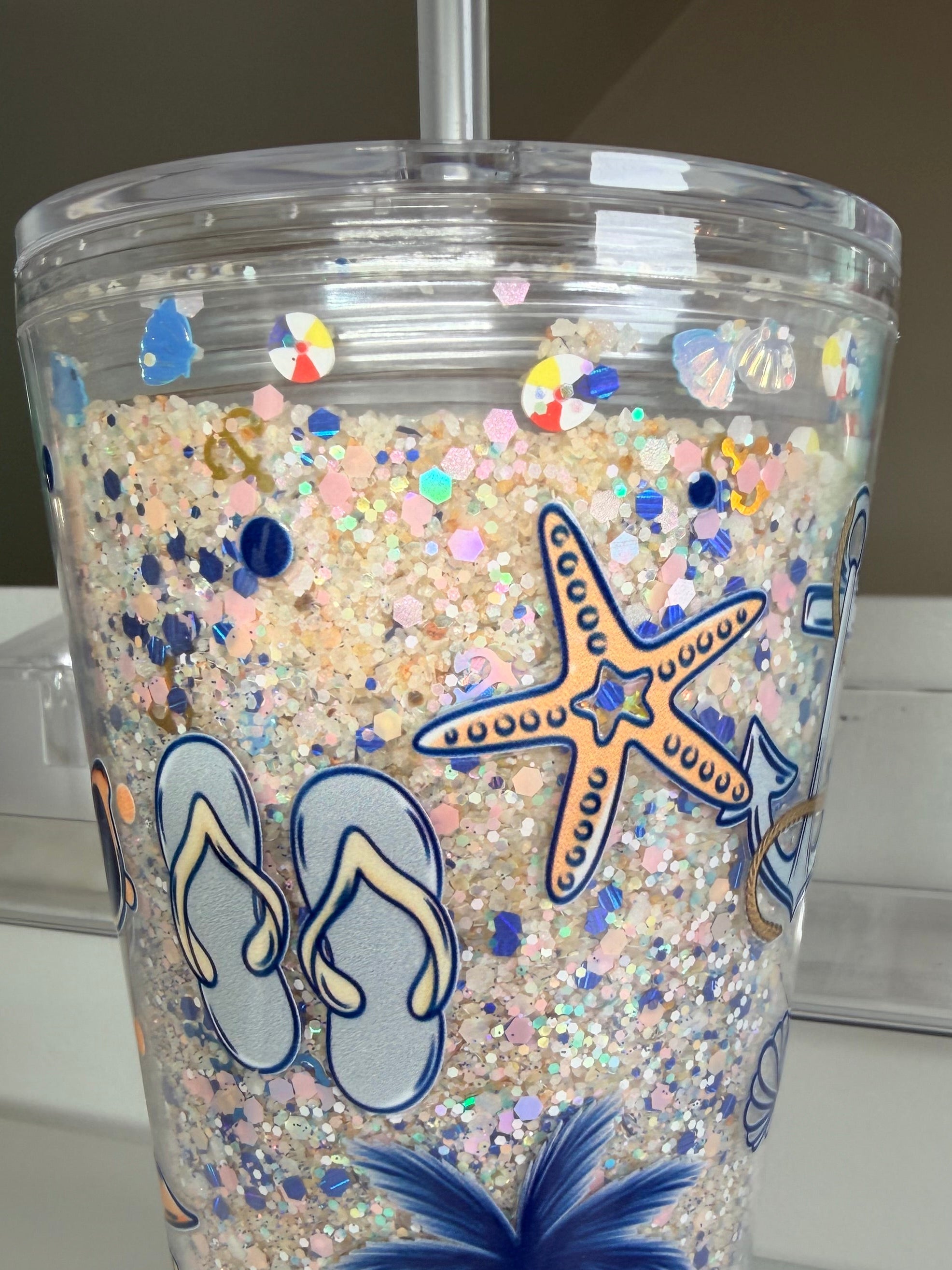 16oz acrylic beach cup close-up: clear glitter with blue starfish, flip-flop and palm art