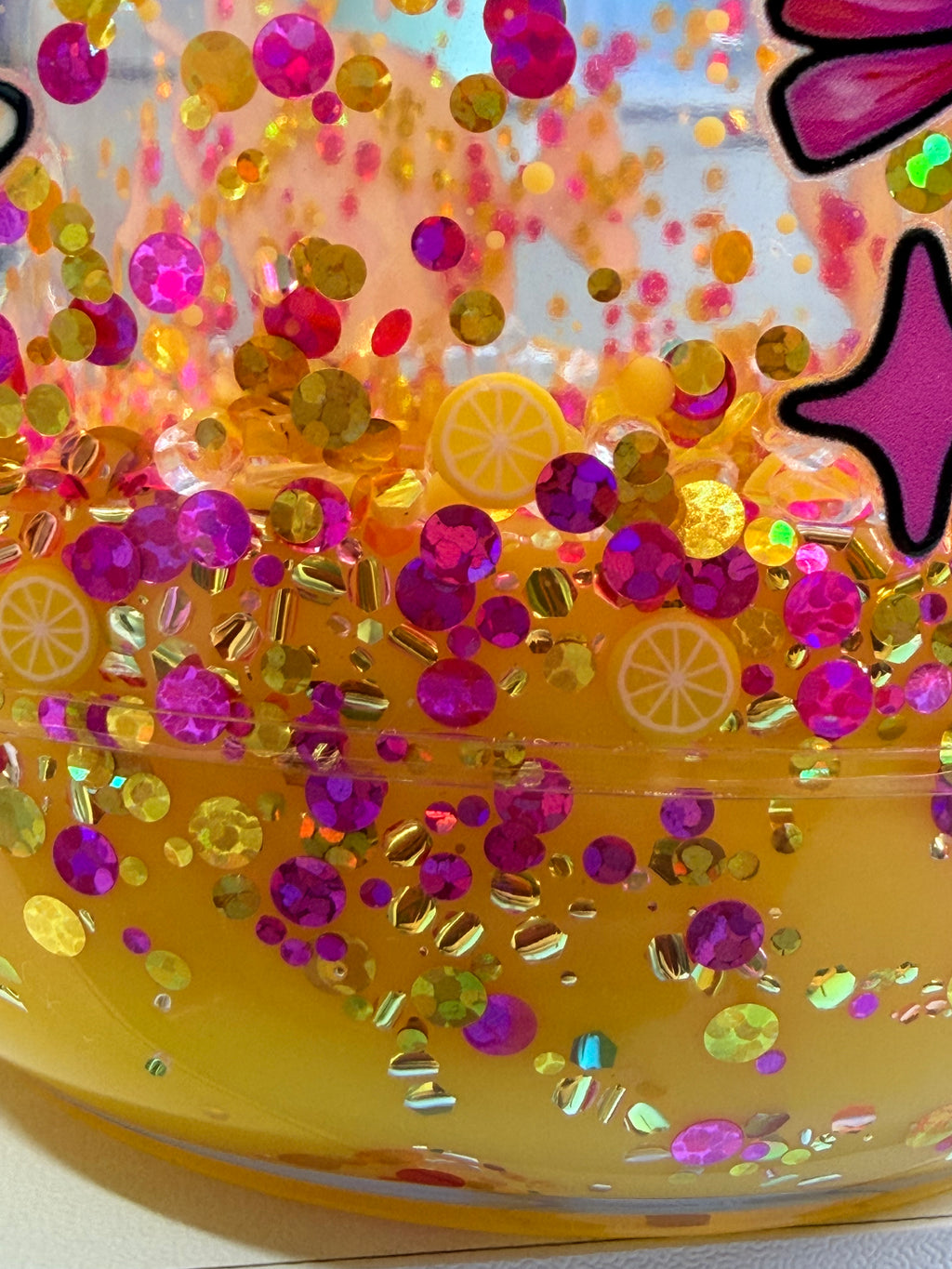Acrylic mason jar close-up of yellow glitter with purple and gold confetti sparkle.