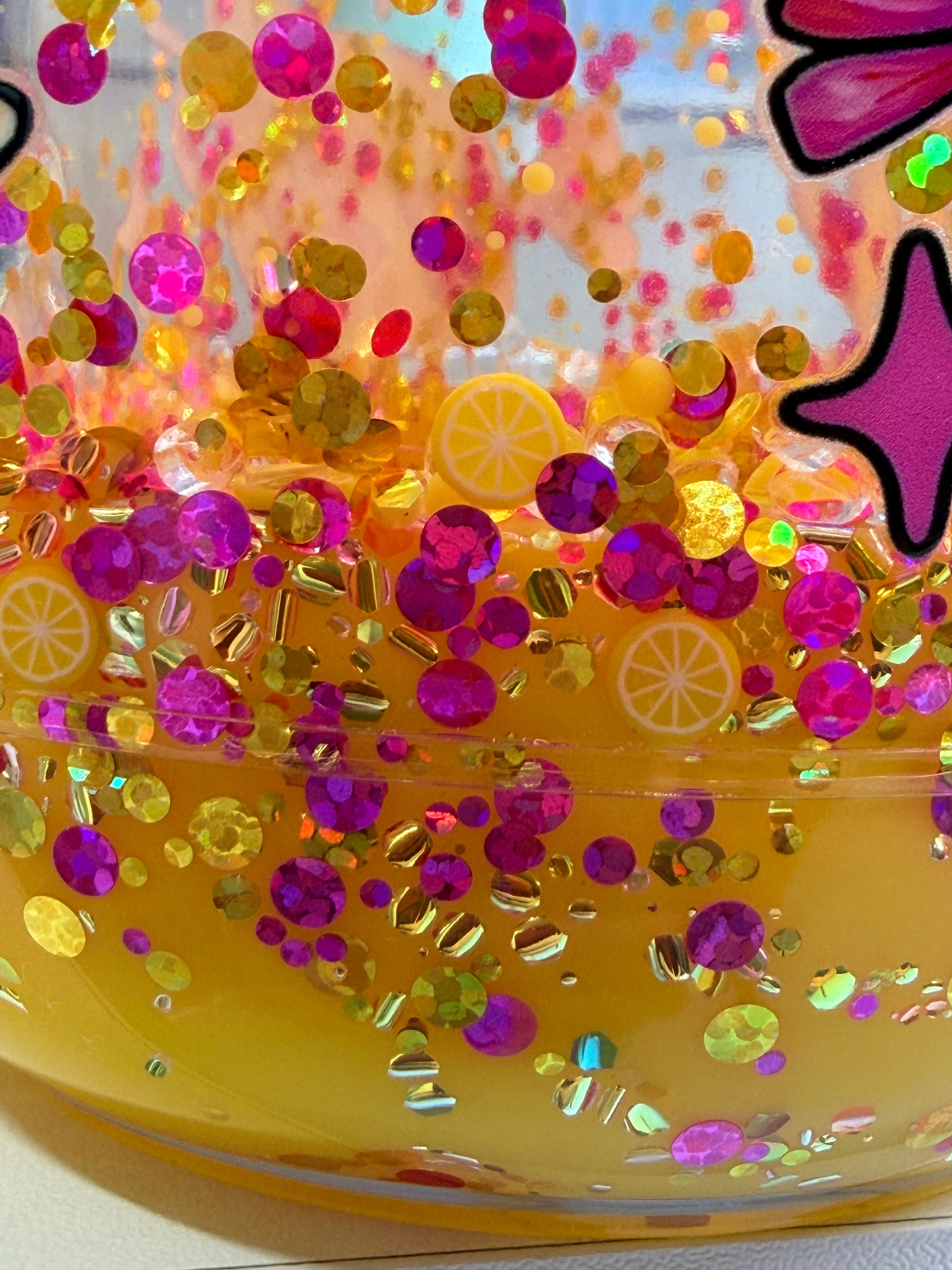 Acrylic mason jar close-up of yellow glitter with purple and gold confetti sparkle.