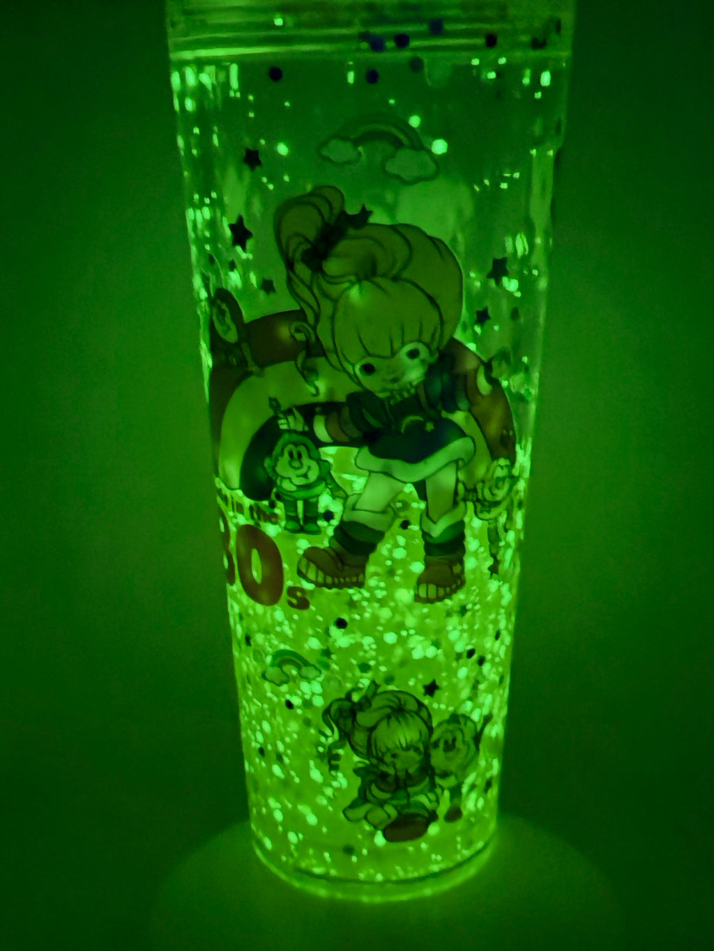 Lava snow globe cup glowing green with character silhouettes, glitter bubbles, straw